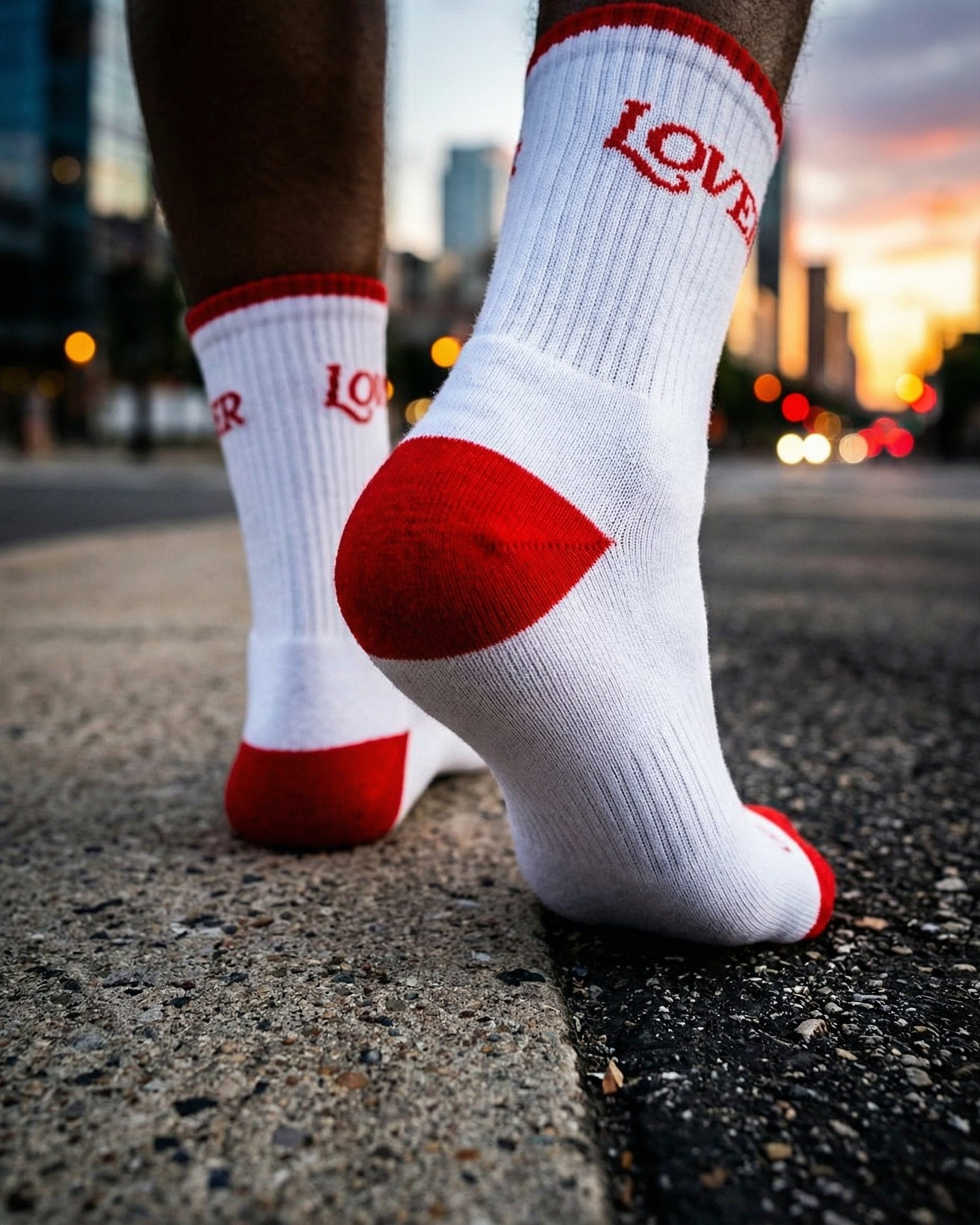 White socks with red accents and 'LOVER' text on a city street. Ruben Rojas Live Through Love