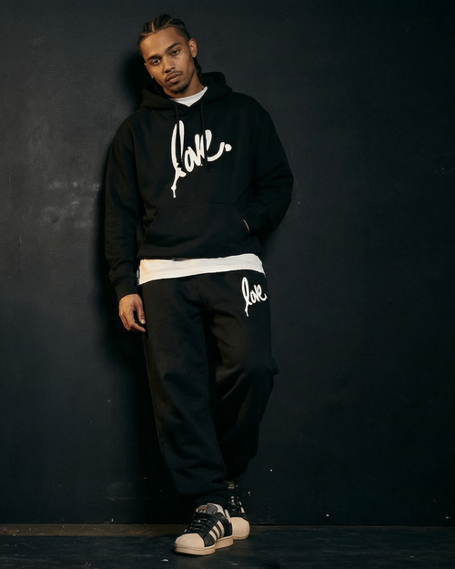 Person wearing a  Ruben Rojas Live Through Love black 'Love' hoodie and original love sweatpants against a dark background