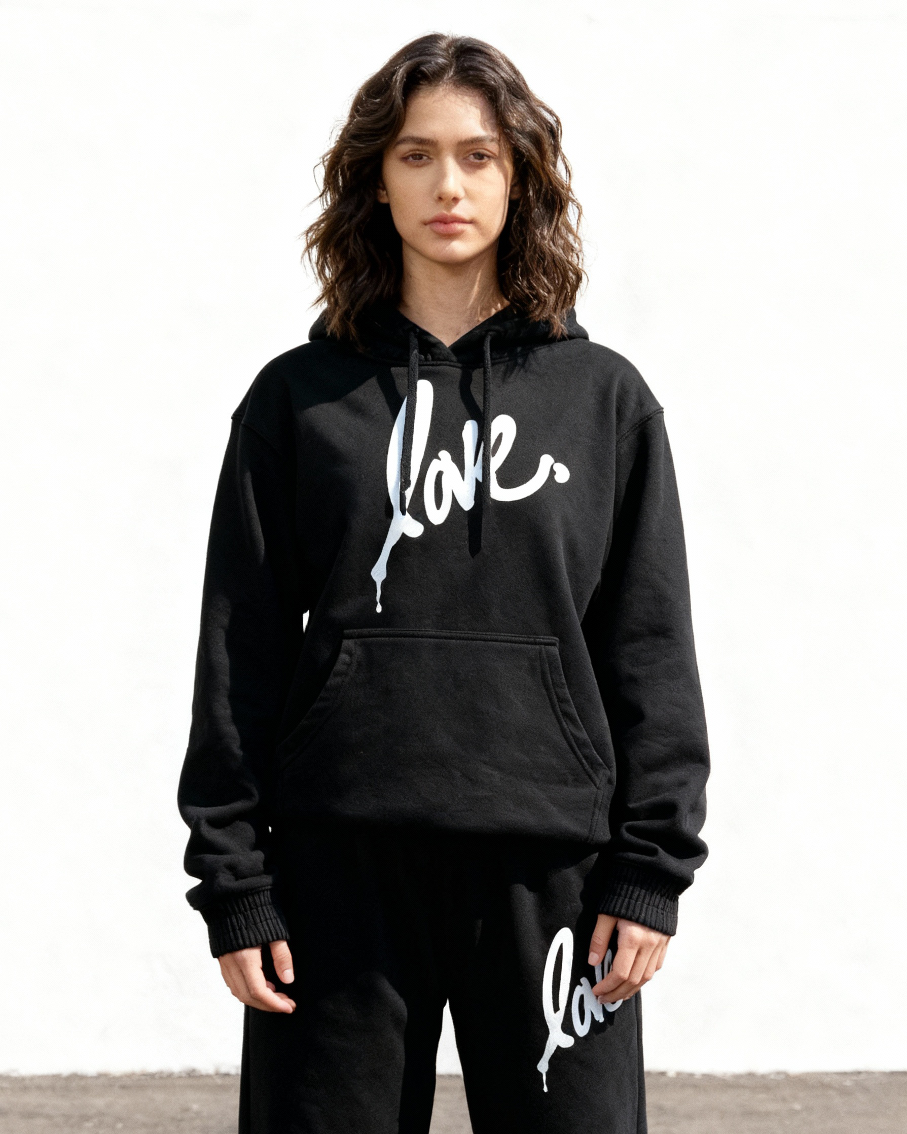 Person wearing a black 'Love' hoodie and pants on a white background