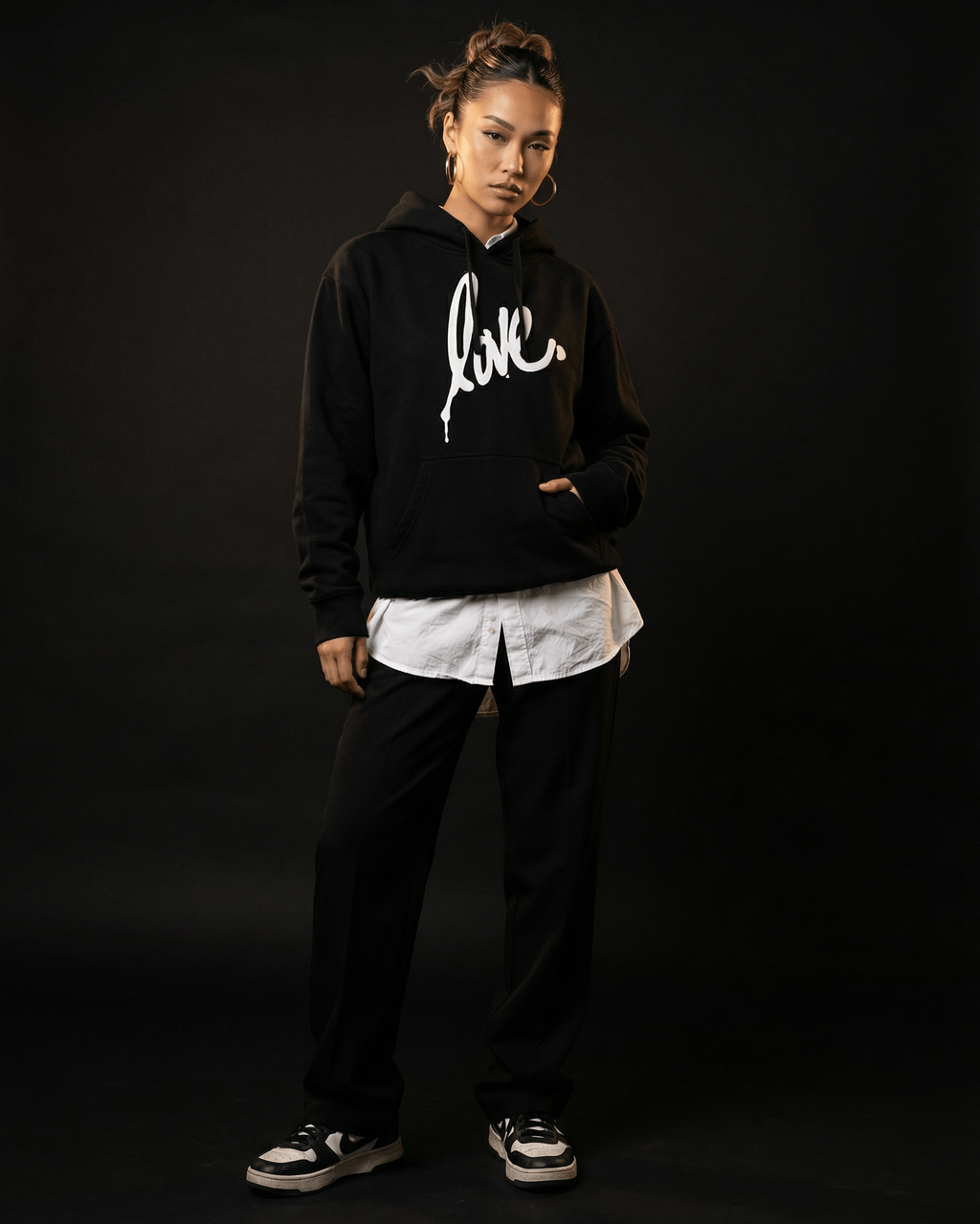 Person wearing a black hoodie Ruben Rojas Live Through Love hoodie with 'love' printed on it against a dark background


