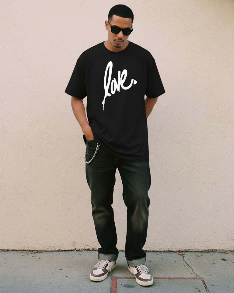 Man wearing a black t-shirt with 'love' printed on it, standing against a beige wall.