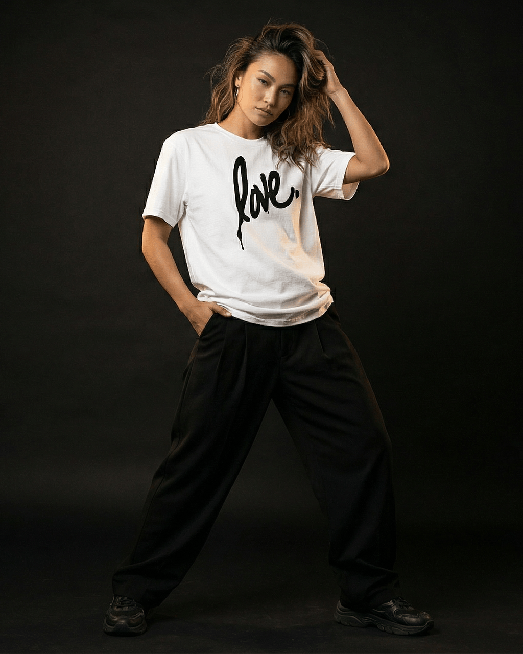 Person wearing a white t-shirt with 'love' printed on it against a black background